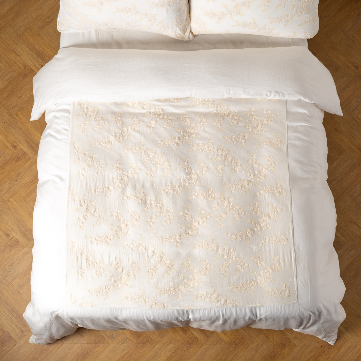 Overhead view of Winter White duvet cover with tonal floral embroidery on a styled bed.