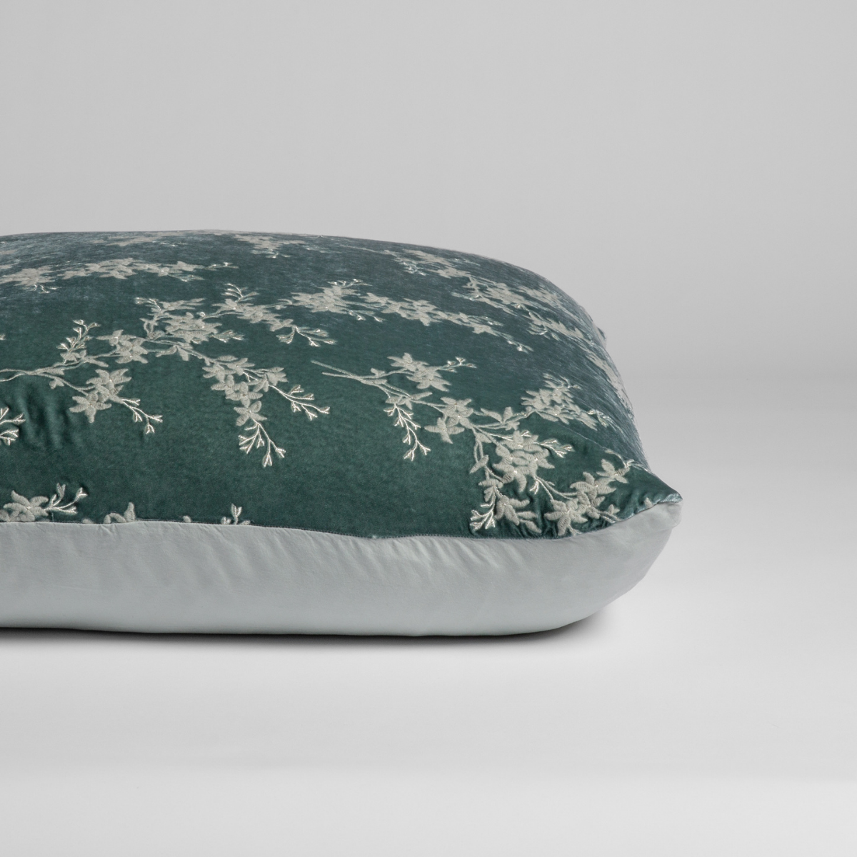 Side-angle view showing Eucalyptus floral embroidery on deep green face with pale reverse.