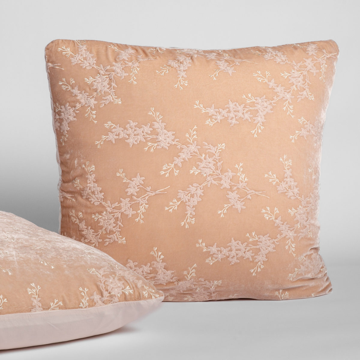 Close-up of Pearl sham with white floral branch embroidery on soft velvet fabric.