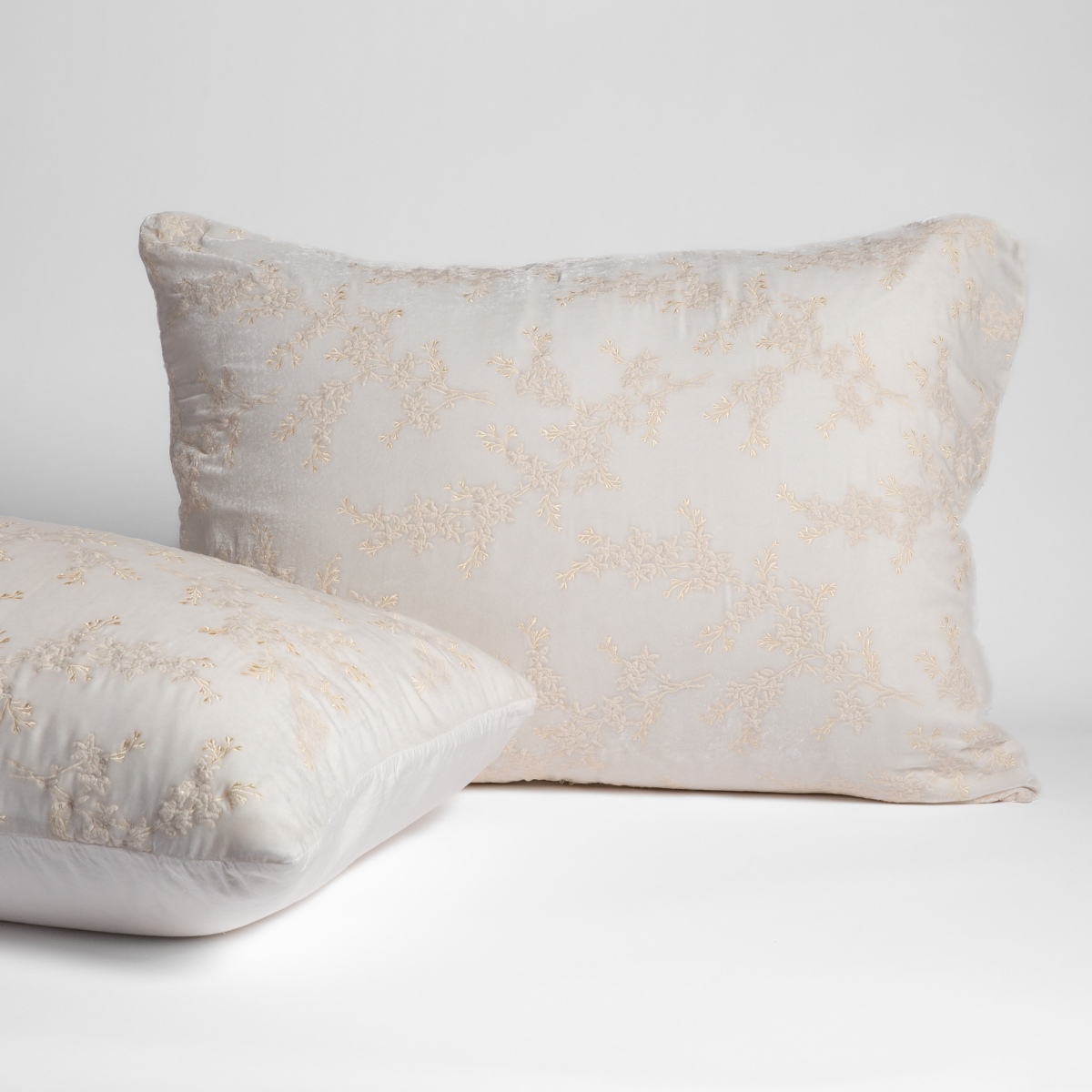 Two Bella Notte Lynette Luxe shams in Winter White with floral embroidery, styled front and back.