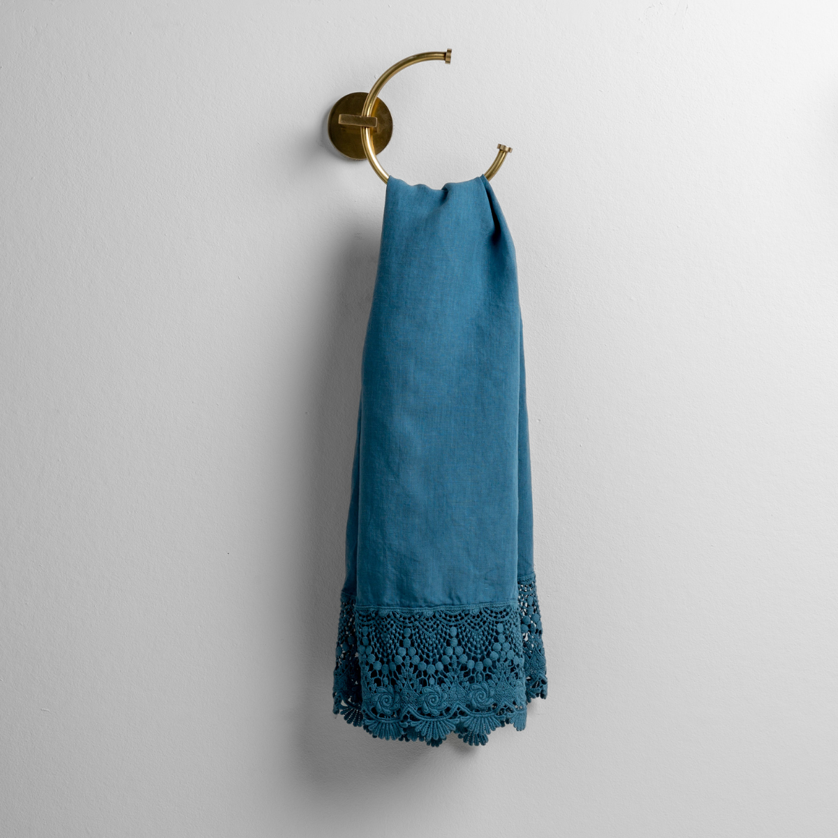 Cenote guest towel draped on brass ring holder, showing lace crochet trim detail at hem.