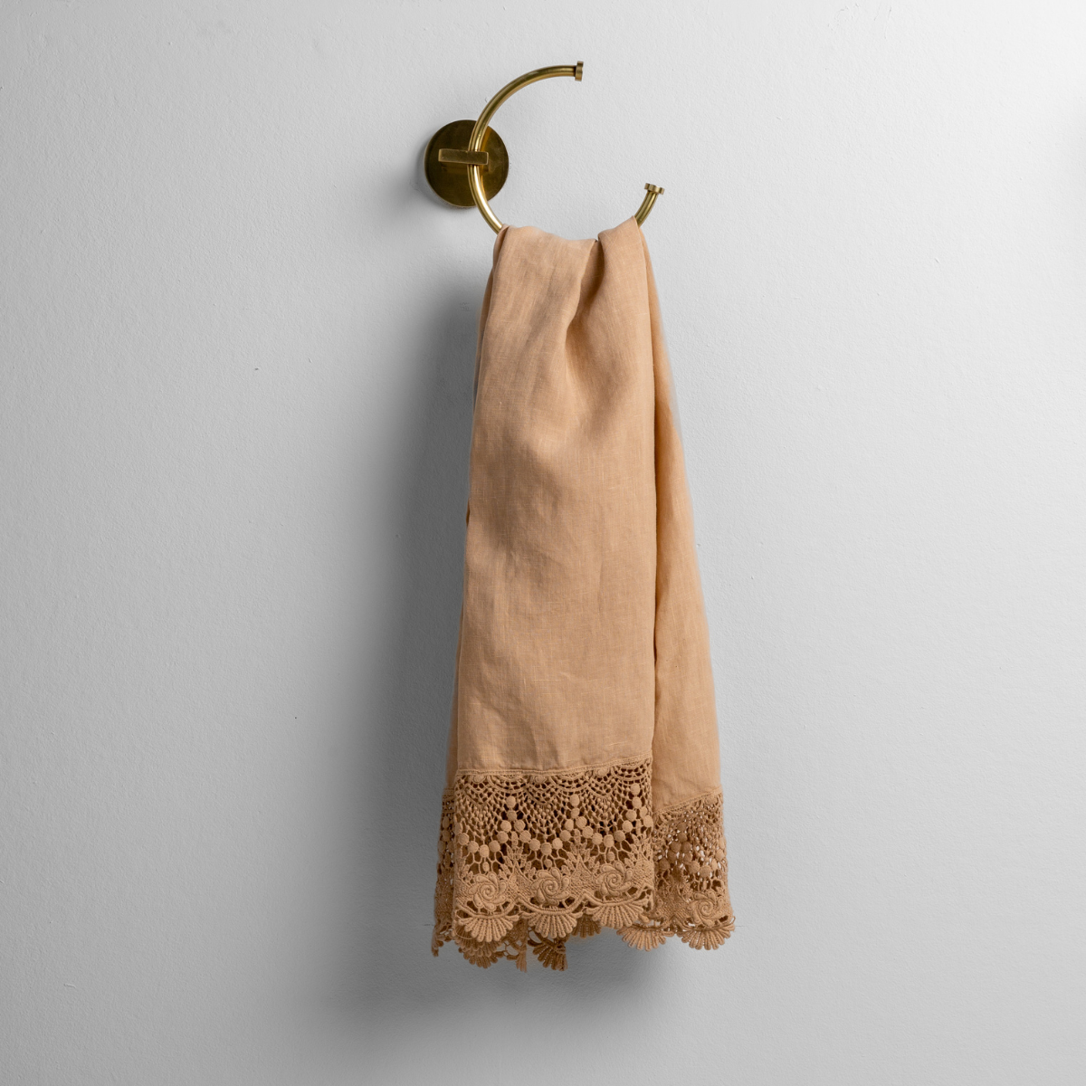 Honeycomb linen guest towel with scalloped crochet lace trim, draped on a brass ring hook.