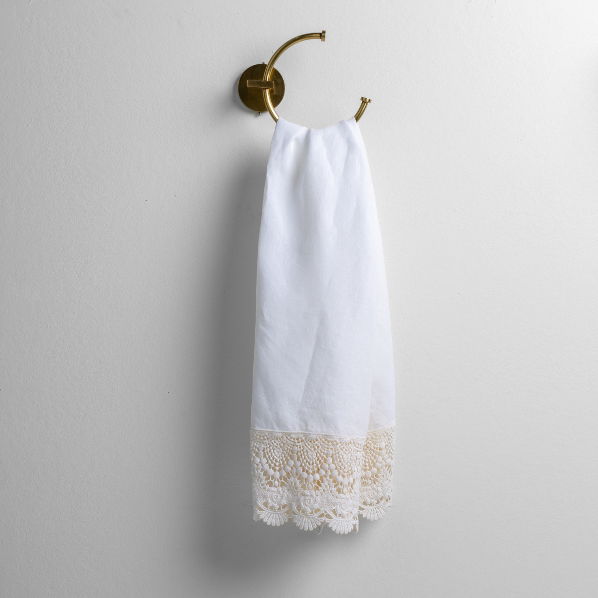 Bella Notte Mattine guest towel in White with ivory crochet lace trim, hung on brass ring.