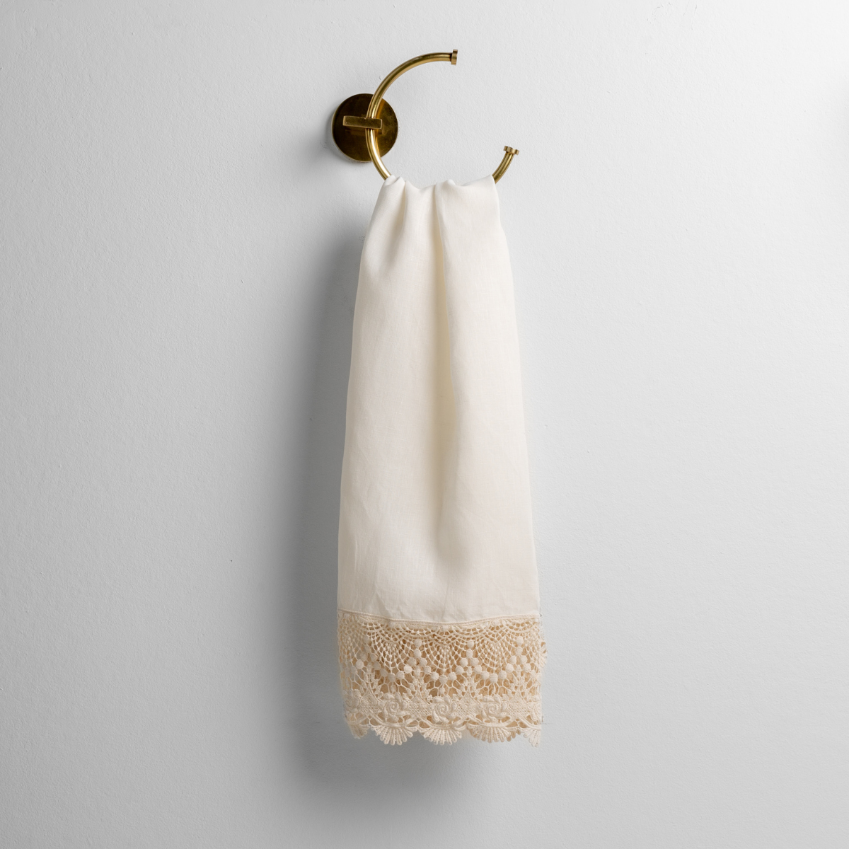 Bella Notte Mattine guest towel in Winter White with intricate scalloped crochet lace trim, hung on brass ring.