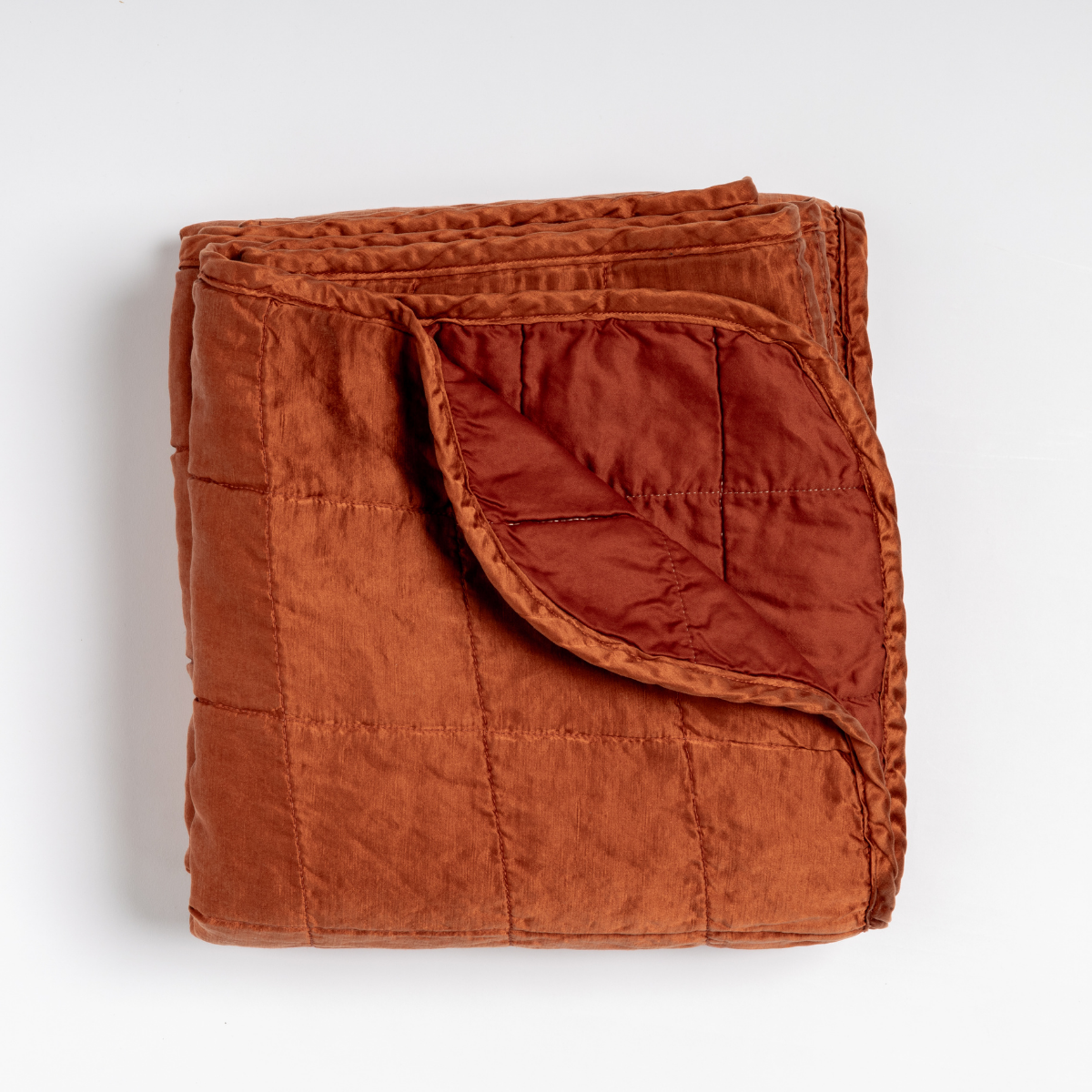 Folded Bella Notte Sel blanket in Autumn, corner turned to reveal quilted lining detail.