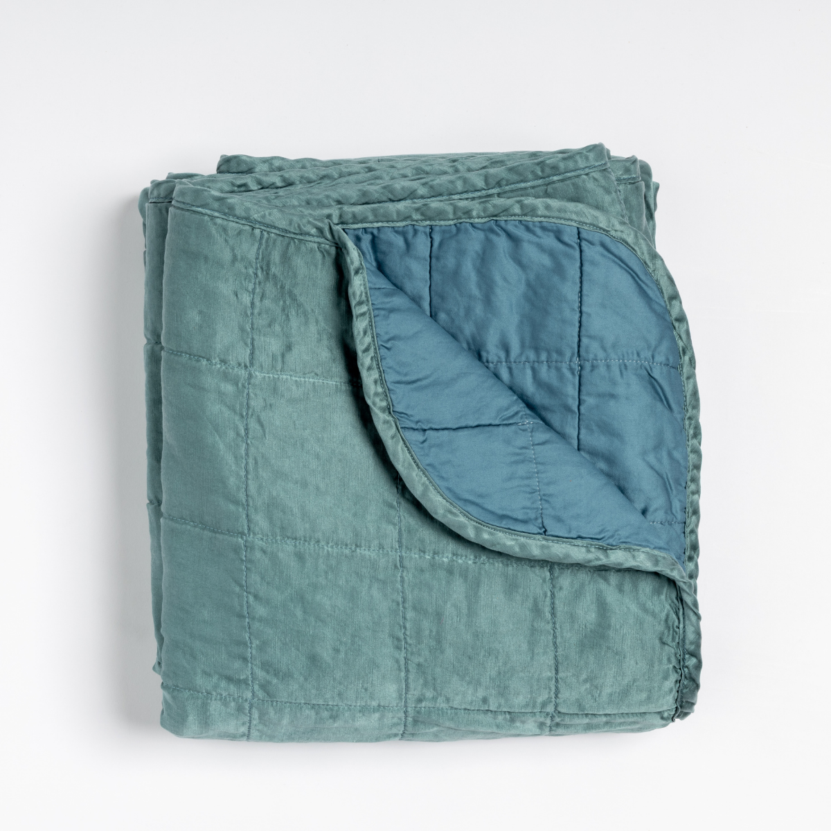 Folded Cenote throw with corner turned back revealing quilted lining and contrast reverse.