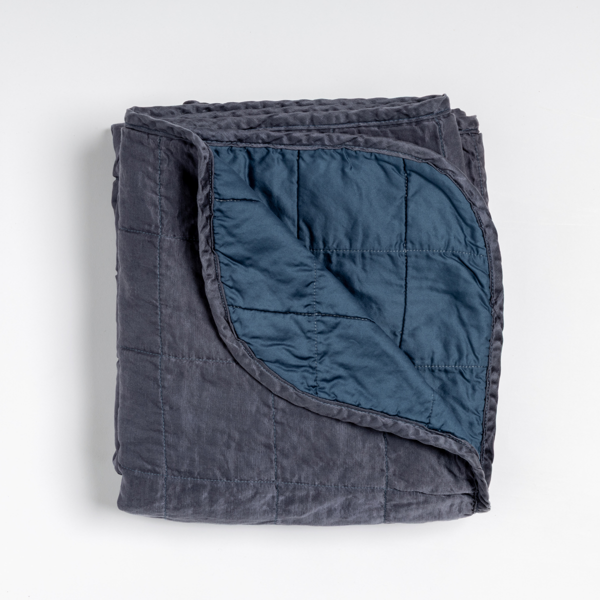 Folded Midnight Sel throw blanket with corner turned back to reveal quilted lining.