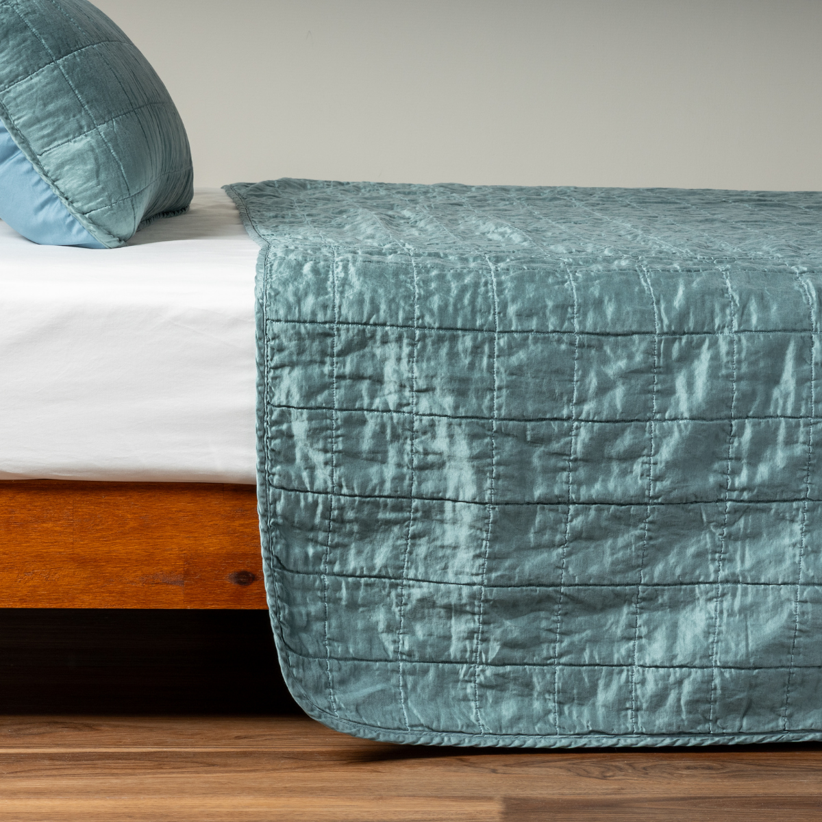 Cenote coverlet draped over foot of bed, showing horizontal quilted stitching detail.
