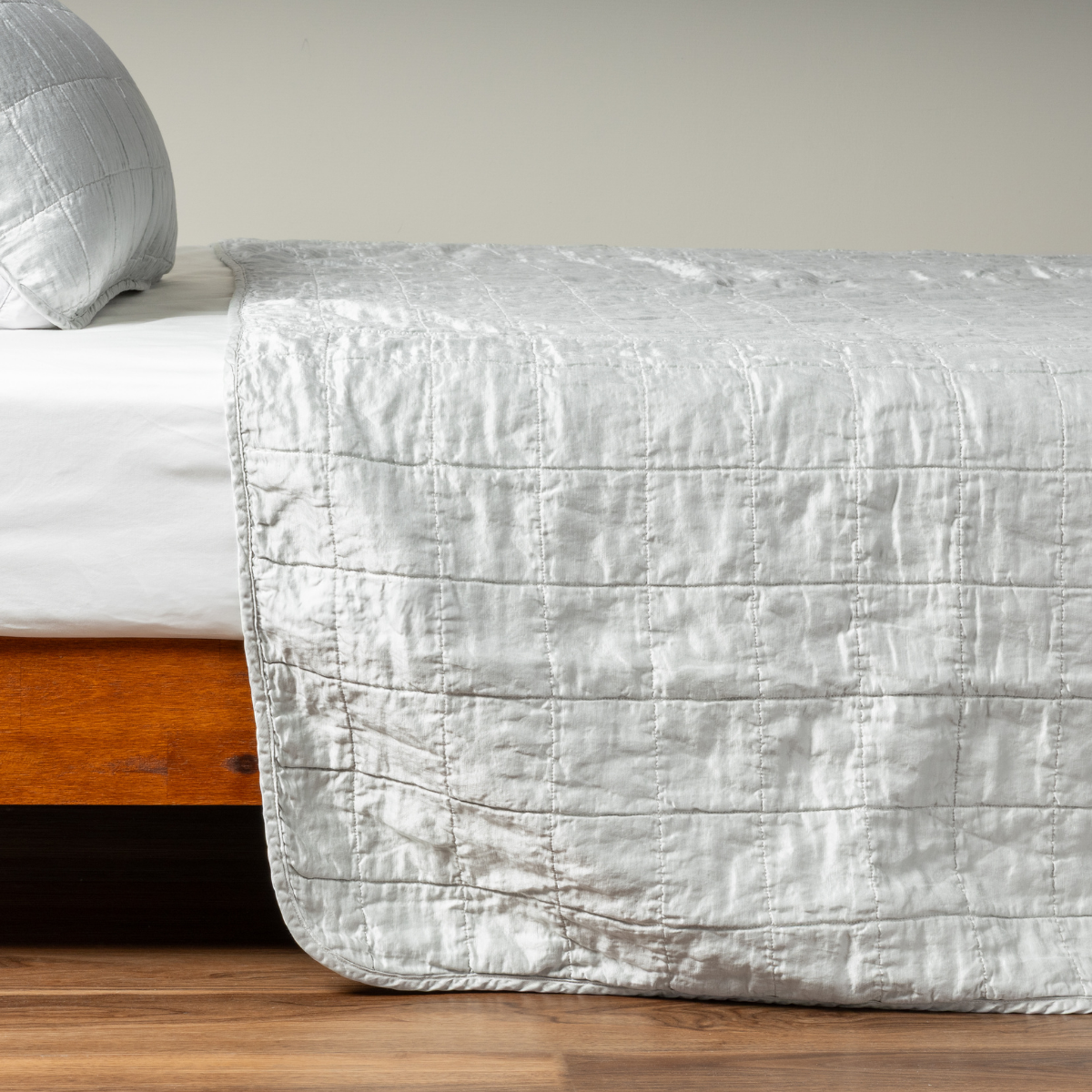 Side view of Bella Notte Sel coverlet in Cloud, showing quilted horizontal stitching draped over bed foot.