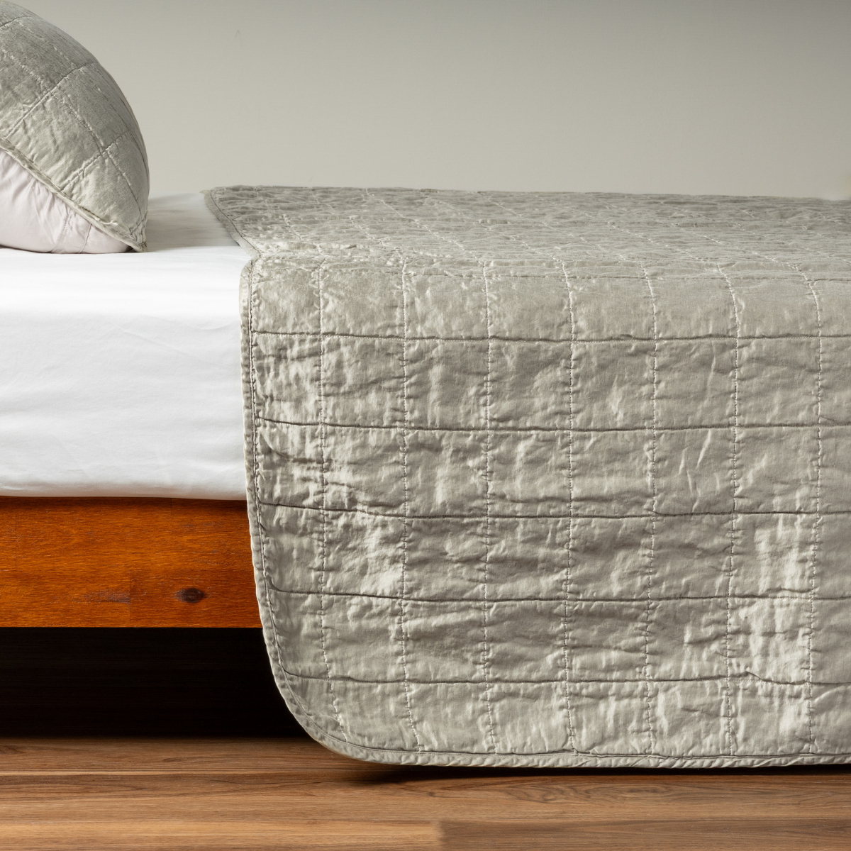 Fog coverlet foot-of-bed drape showing quilted grid stitching detail on wood-frame bed.