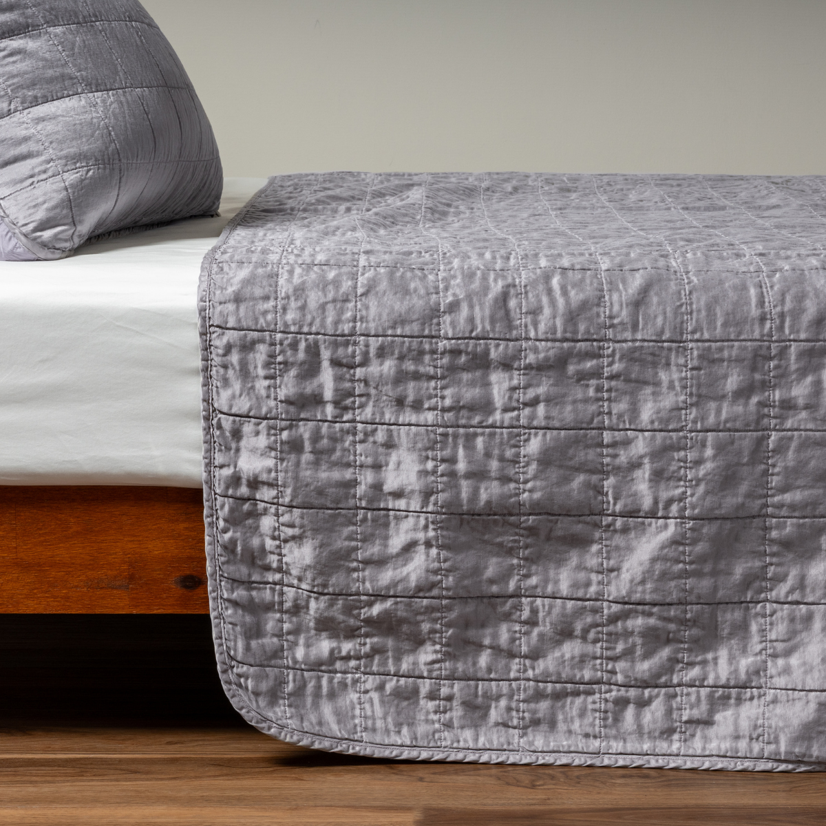 French Lavender coverlet draped over bed foot, showing grid quilting and relaxed linen texture.
