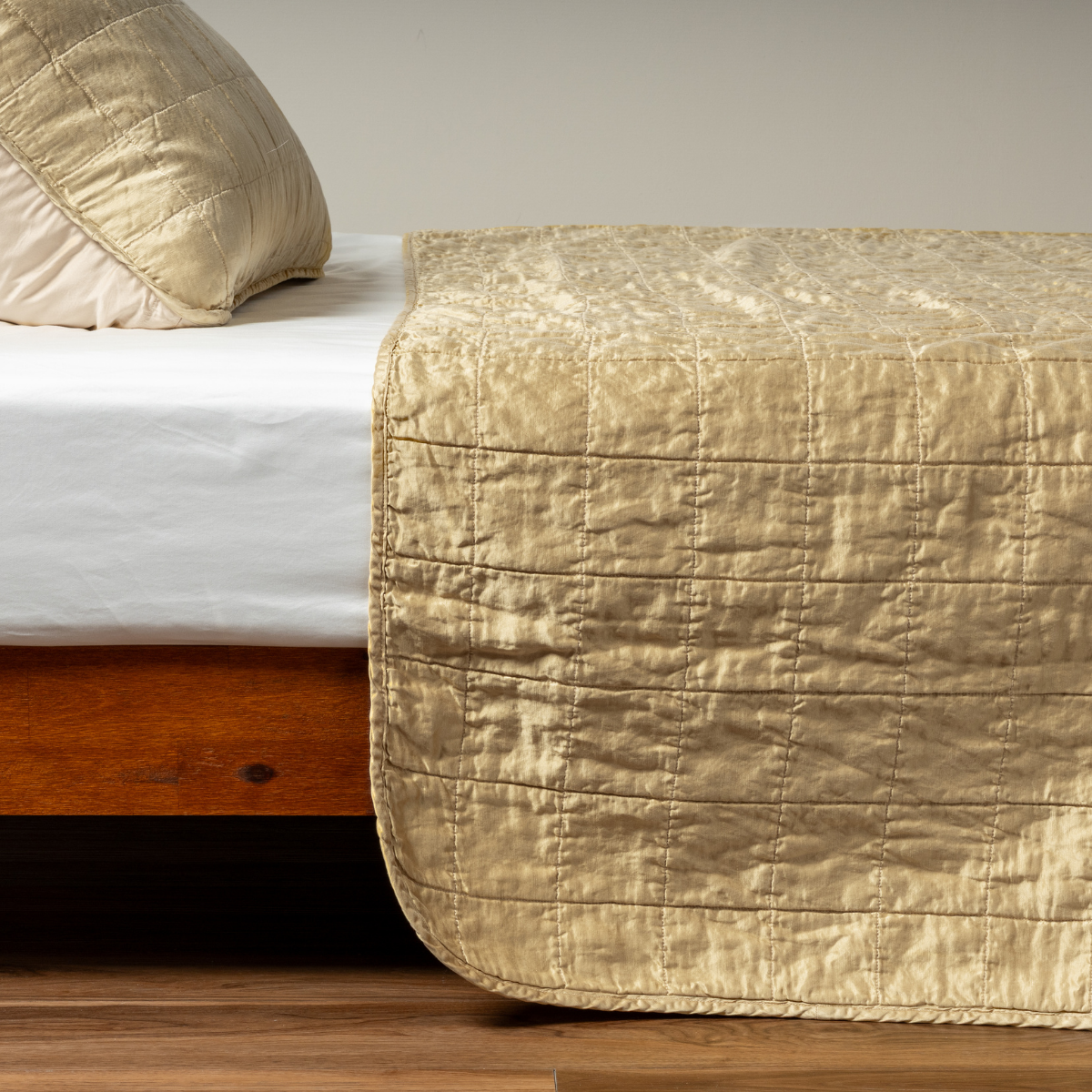 Honeycomb Sel coverlet draped over bed foot, showing quilted grid stitching detail.