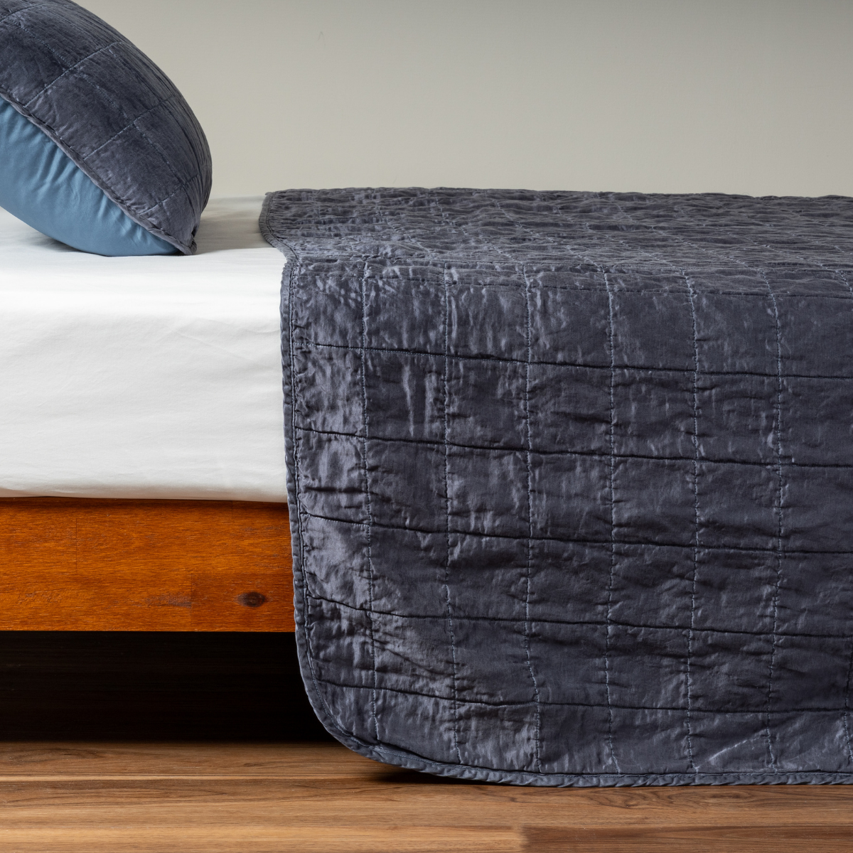 Midnight Sel coverlet draped over bed foot, showing quilted grid stitching on lustrous velvet.