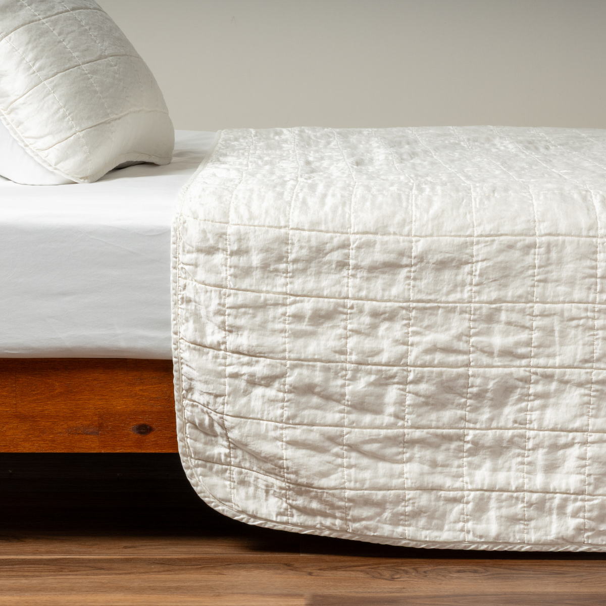 Winter White quilted coverlet draped over bed foot, showing grid-stitched texture and soft drape.