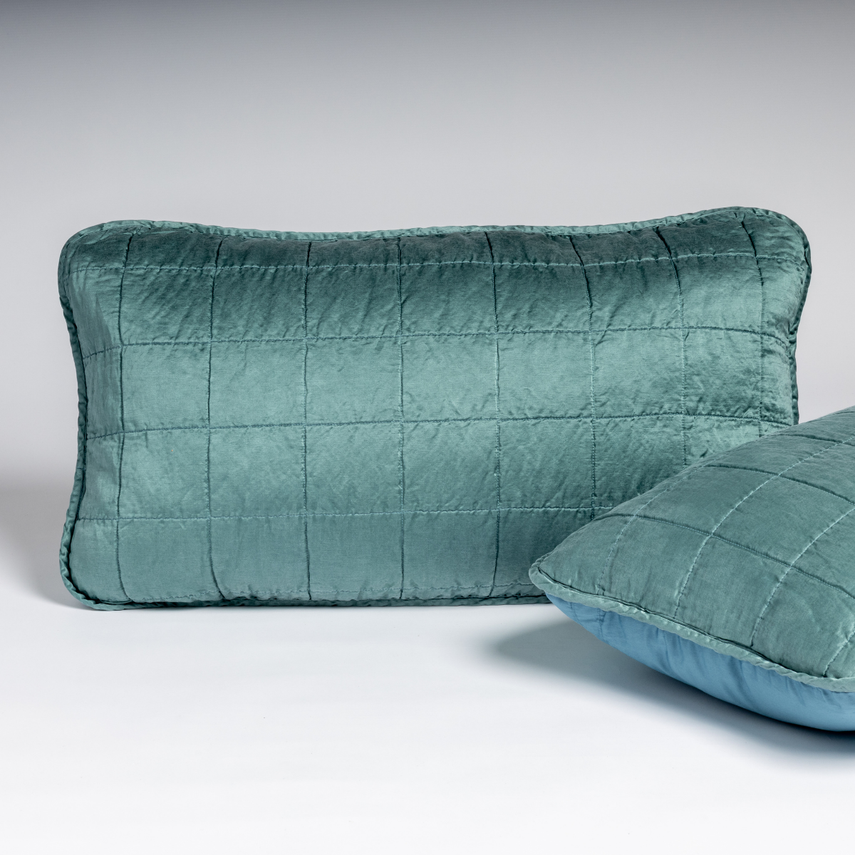 Cenote velvet lumbar sham with grid quilting, second pillow partially visible in foreground.