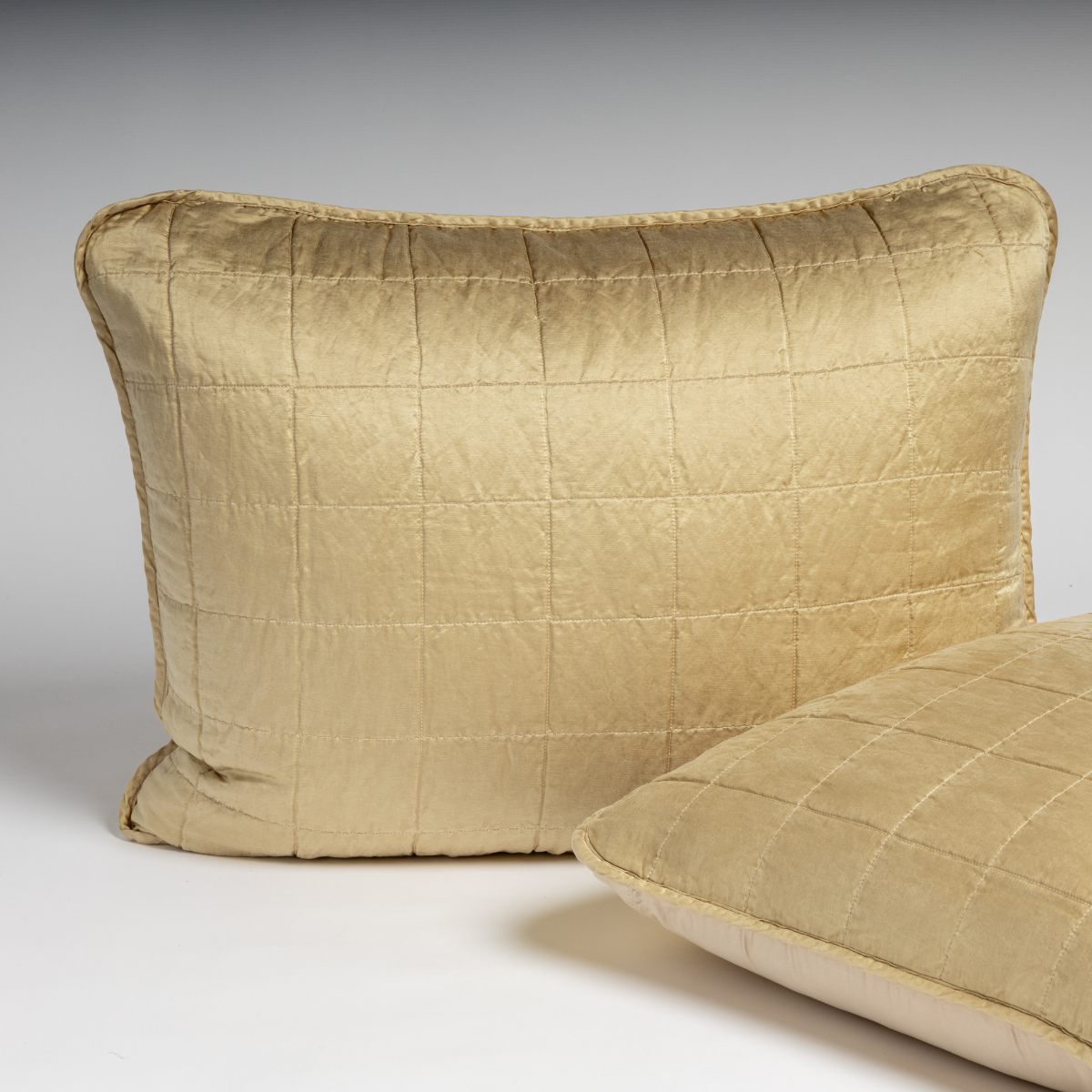 Honeycomb quilted silk sham with grid stitching and contrast piped trim, angled view.