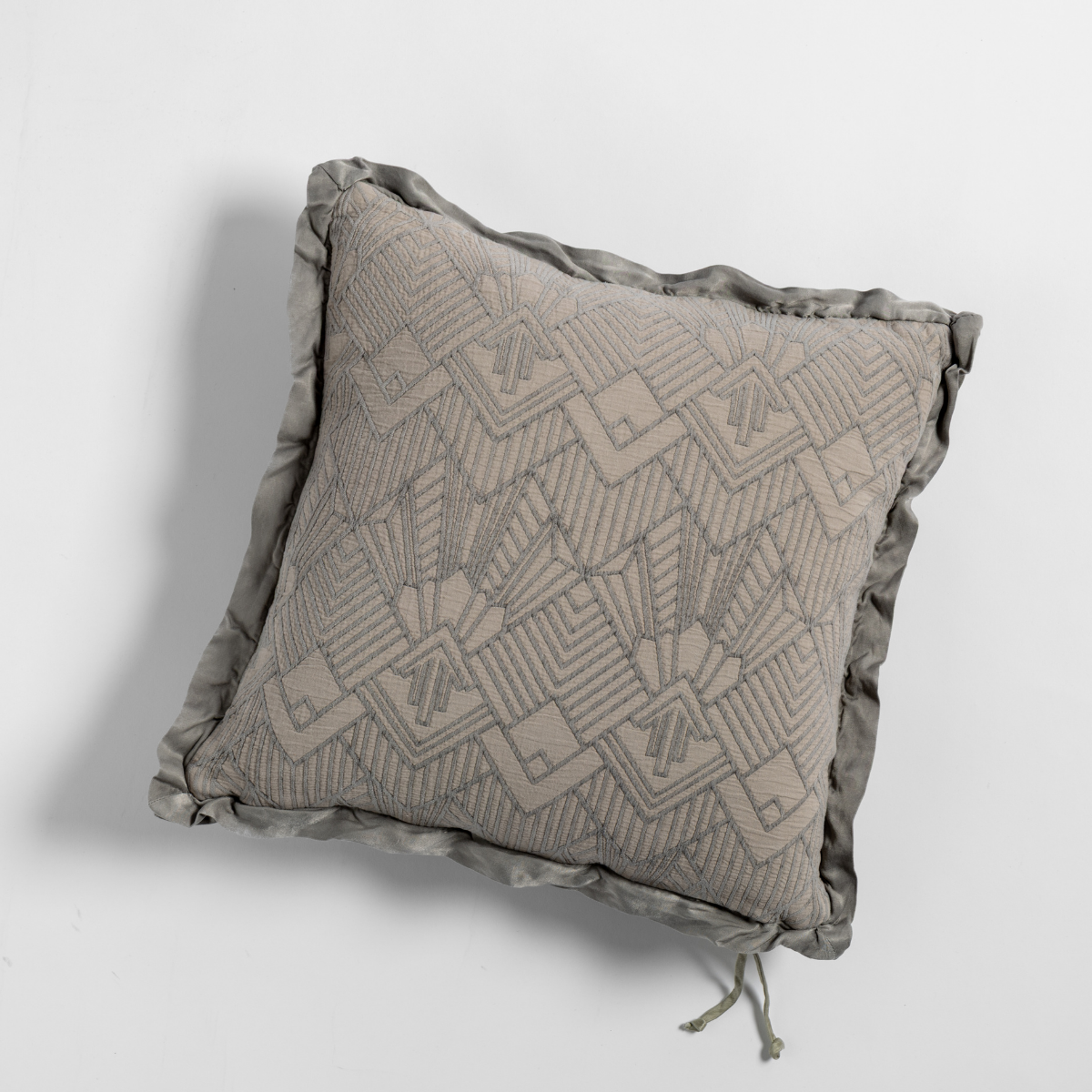 Fog Trettino throw pillow showing geometric embroidery and ruffled edge trim, overhead view.
