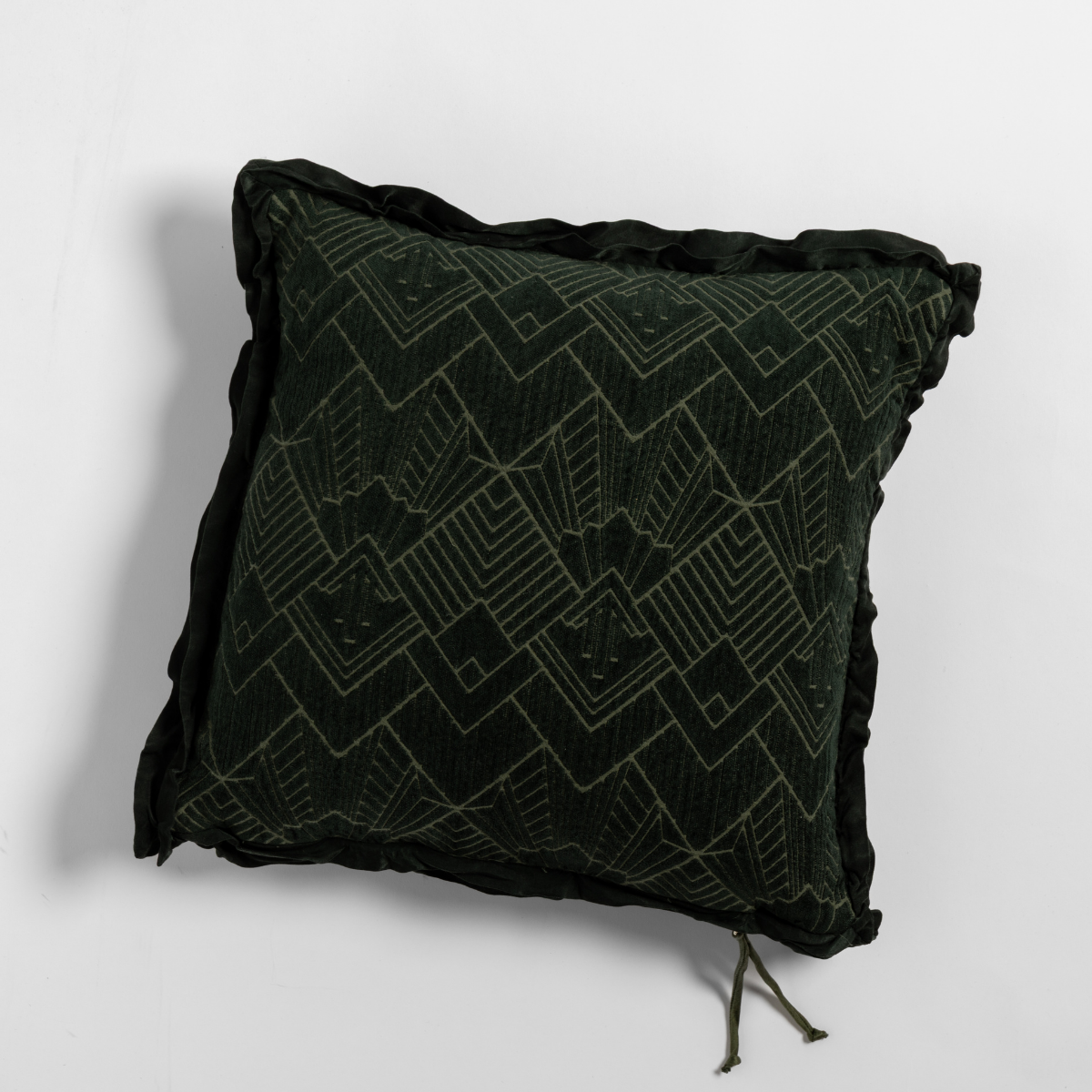Dark Juniper velvet throw pillow with geometric embroidery and ruffled trim, shot at an angle.