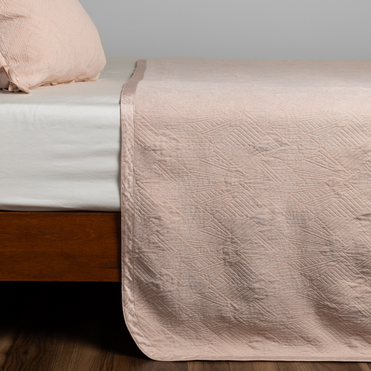 Bella Notte Trettino bedspread in Pearl draped over bed foot, showing quilted texture detail.