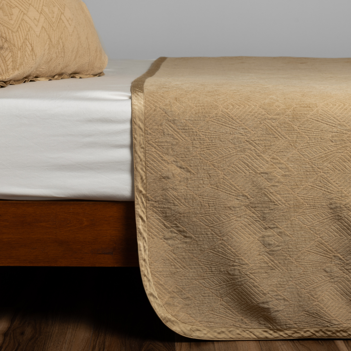 Honeycomb bedspread draped over bed foot, showing quilted geometric texture and corner drape.