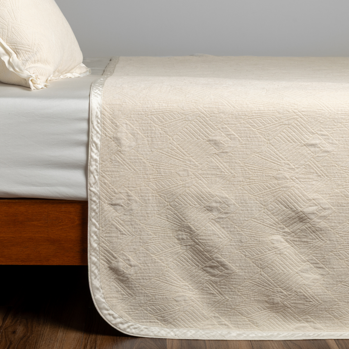 Bella Notte Trettino bedspread in Natural, draped over bed showing quilted texture detail.