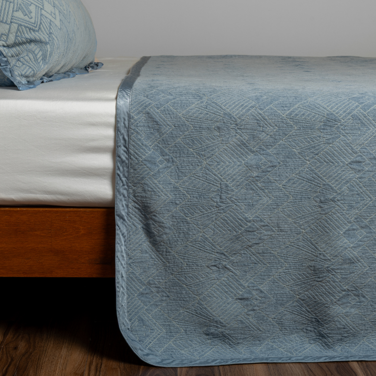 Tahoe Blue bedspread draped over bed corner, showing quilted geometric texture and matte finish.