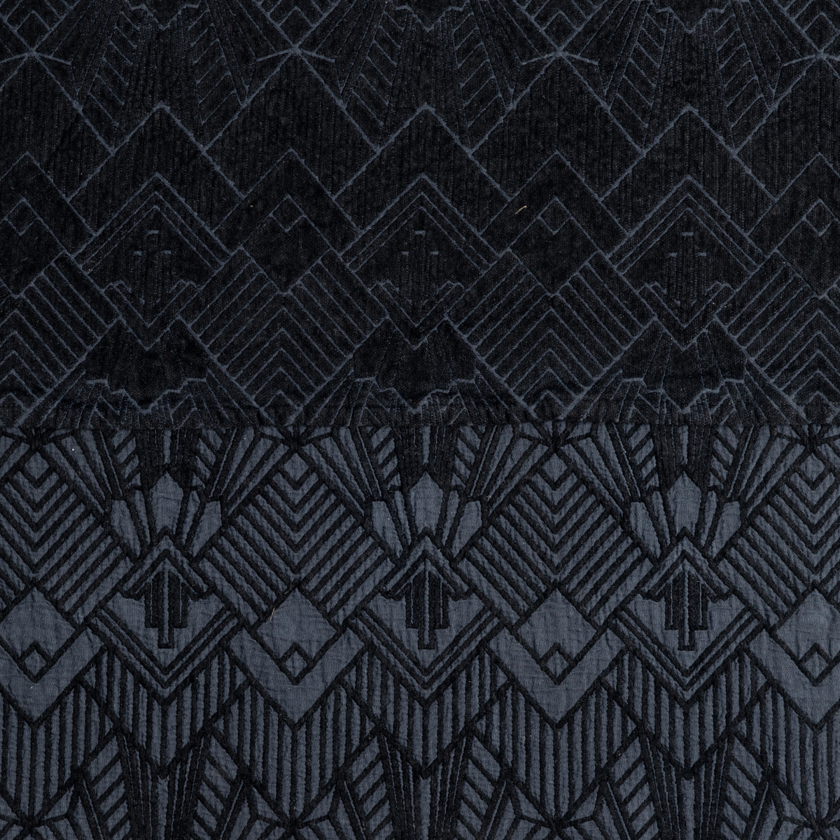 Close-up of Corvino Trettino bedspread showing Art Deco geometric velvet pattern in deep black-charcoal.