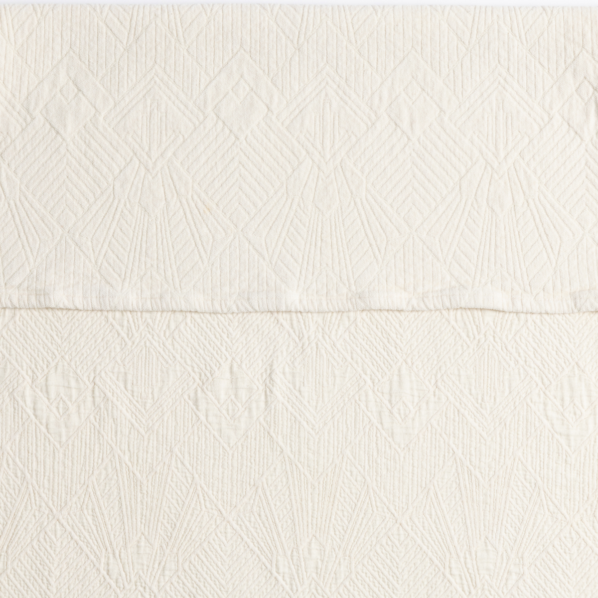 Close-up of Bella Notte Trettino sham in Natural, showing geometric diamond matelassé texture.