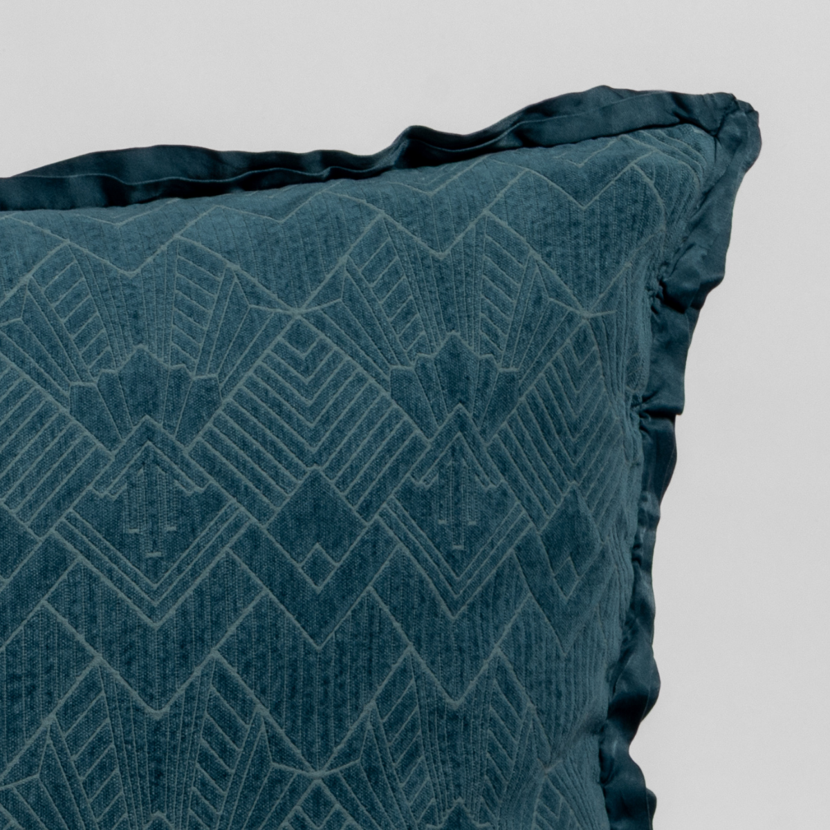 Close-up of Cenote Trettino throw pillow corner showing geometric jacquard pattern and ruffled edge.