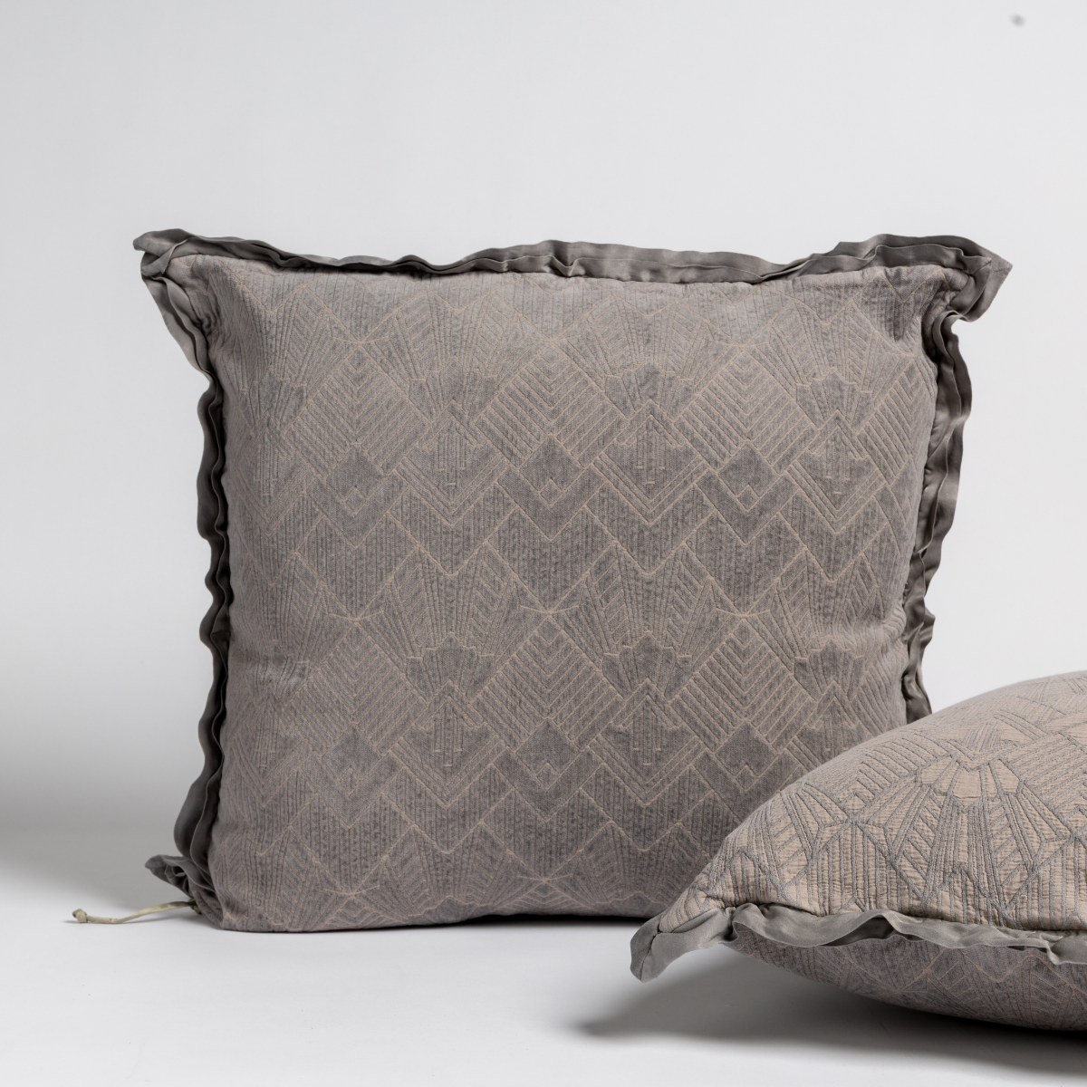 Fog Trettino sham with geometric diamond jacquard and ruffled trim, second sham visible at right.