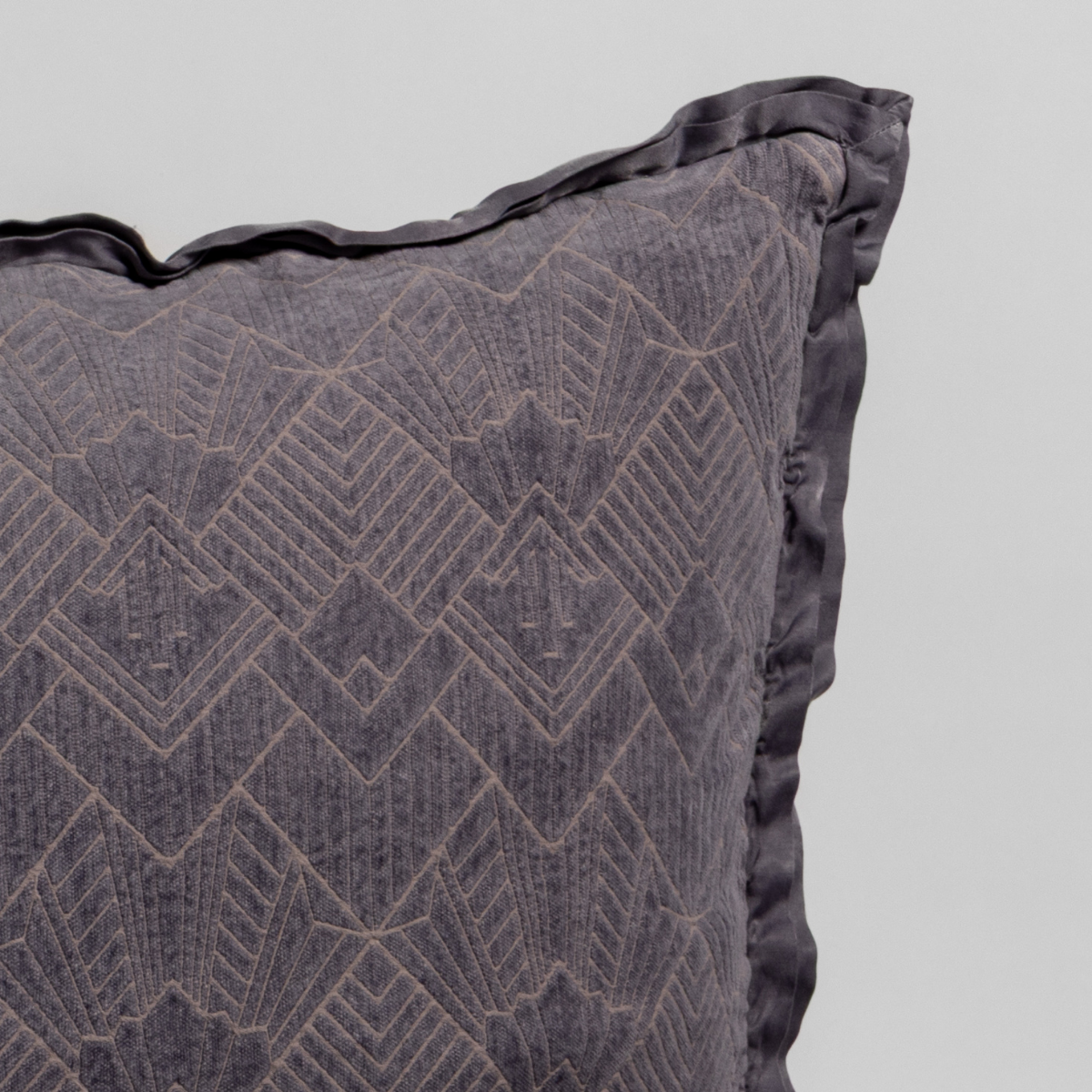 Close-up of French Lavender sham corner showing geometric diamond embroidery and satin trim detail.