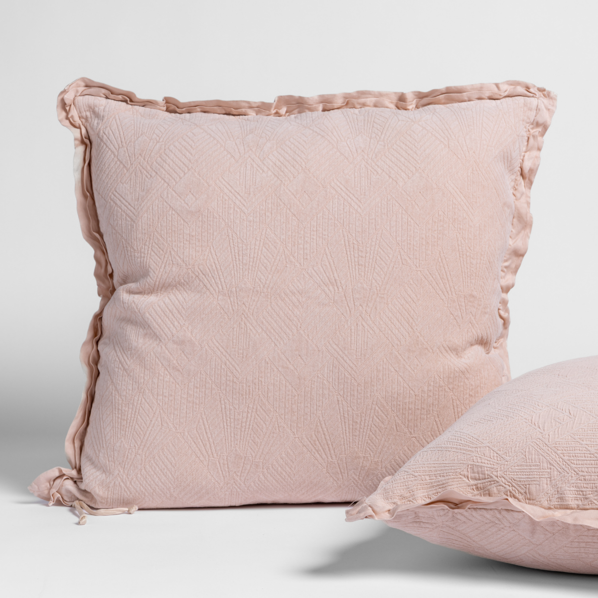 Bella Notte Trettino sham in Pearl with ruffled trim and subtle woven texture, two cushions styled.