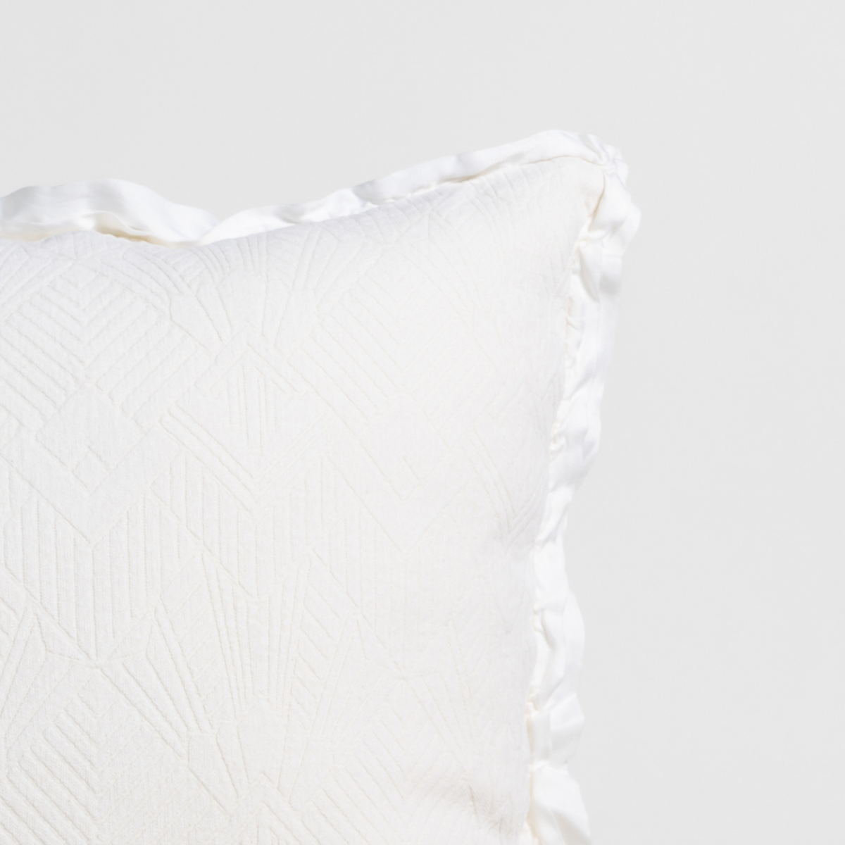 Close-up corner of Winter White Bella Notte Trettino throw pillow showing woven texture and satin trim.