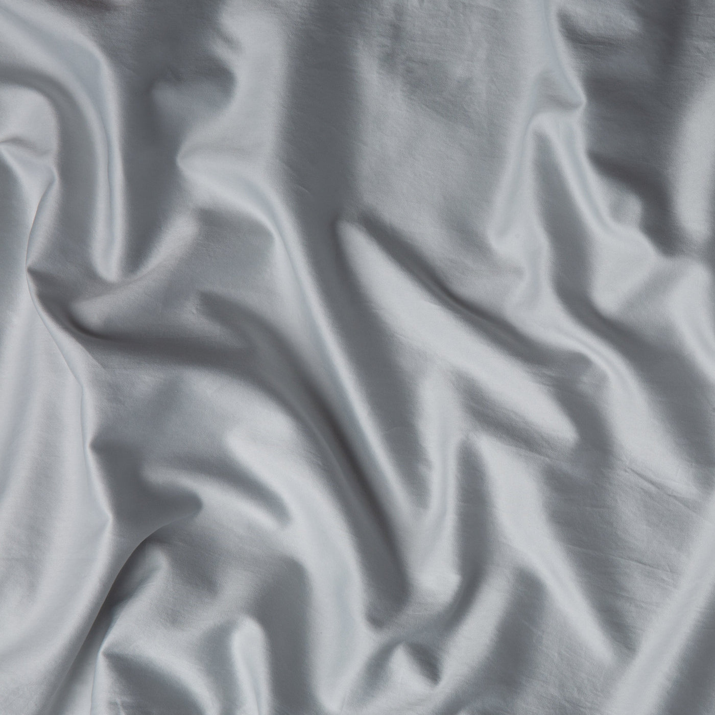 Close-up of Bella Notte Bria fitted sheet in Cloud, showing silky fabric drape and sheen.