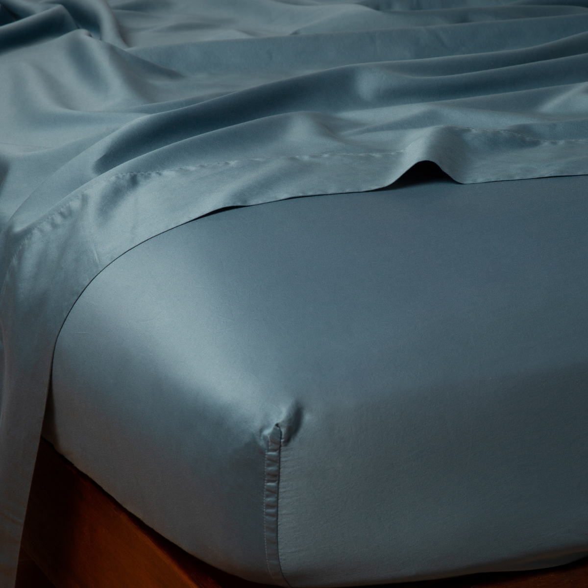 Close-up corner of Bella Notte Bria fitted sheet in Cenote, showing lustrous drape and deep pocket fit.