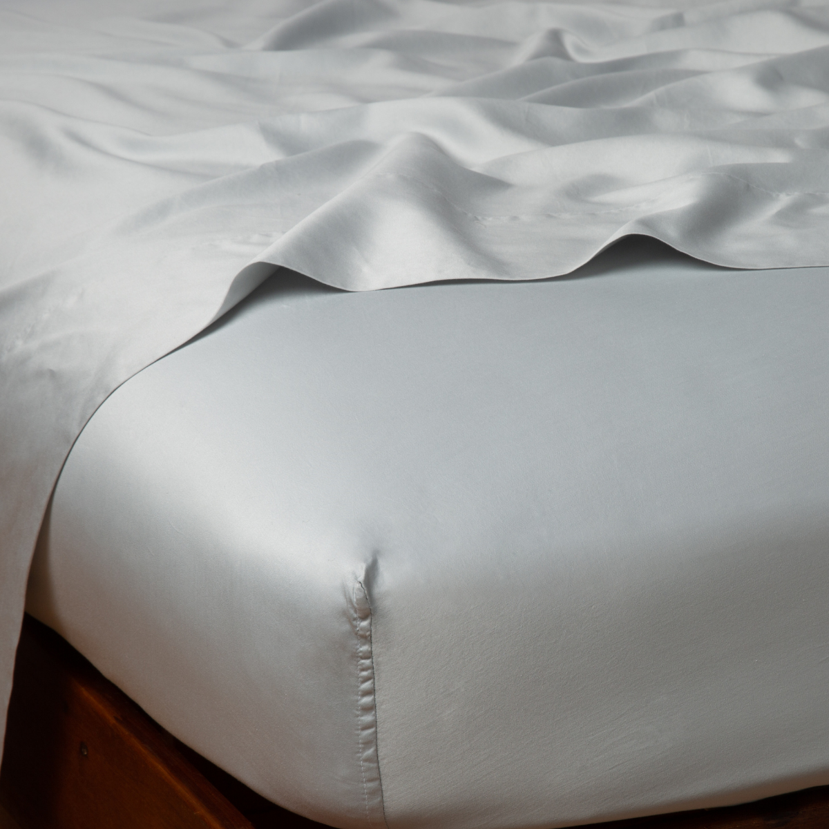 Close-up of Bella Notte Bria fitted sheet corner in Cloud, showing silky sheen and snug fit.