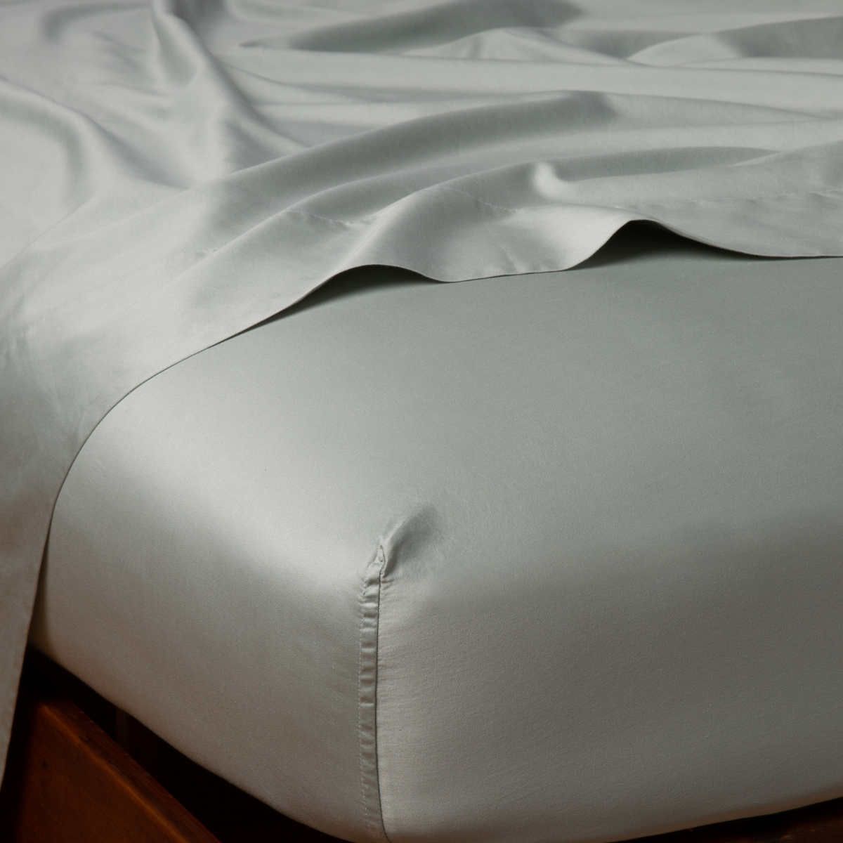 Close-up of Bella Notte Bria fitted sheet corner in Eucalyptus, showing silky drape and tailored fit.