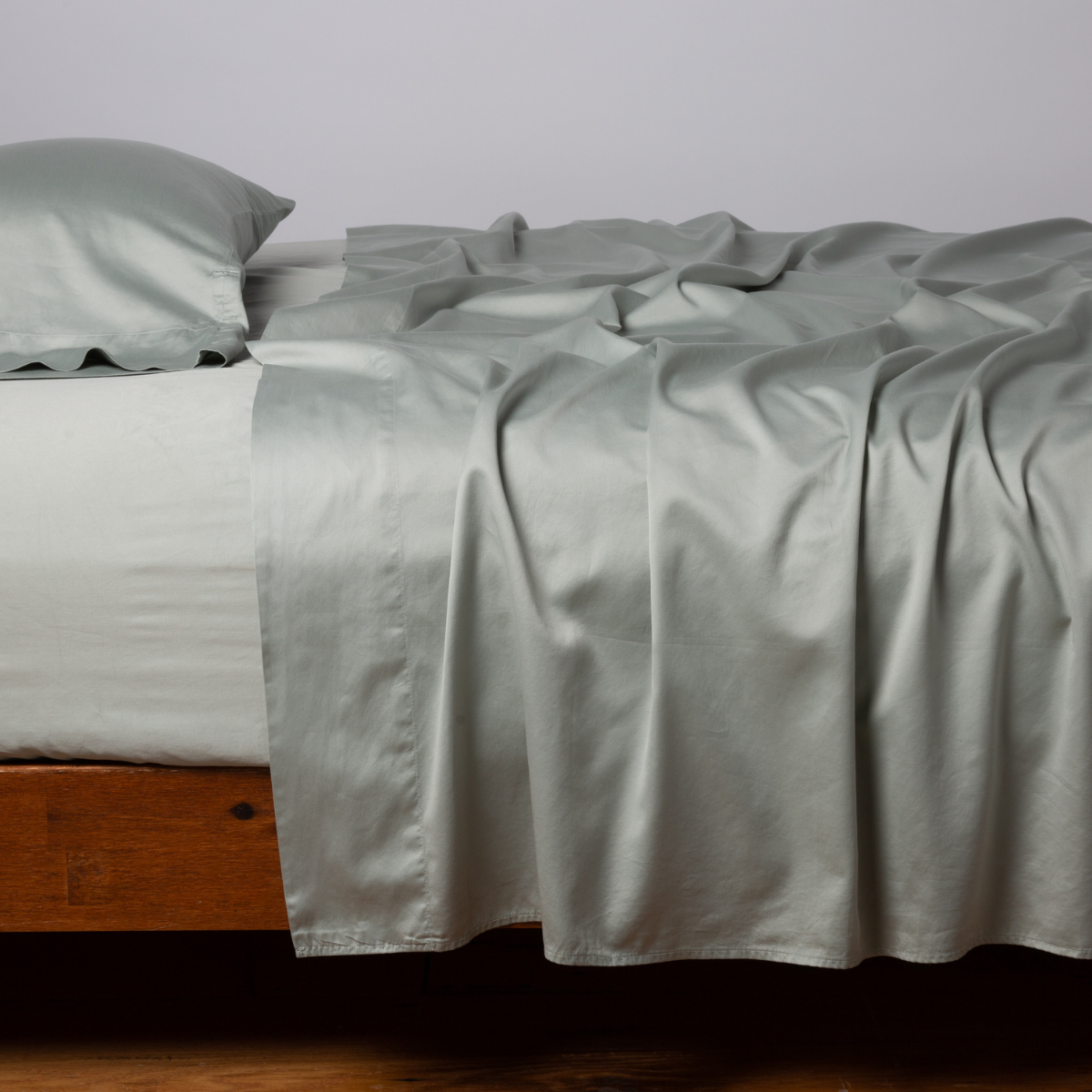 Eucalyptus fitted sheet draped casually over a wood-frame bed with matching pillowcases.