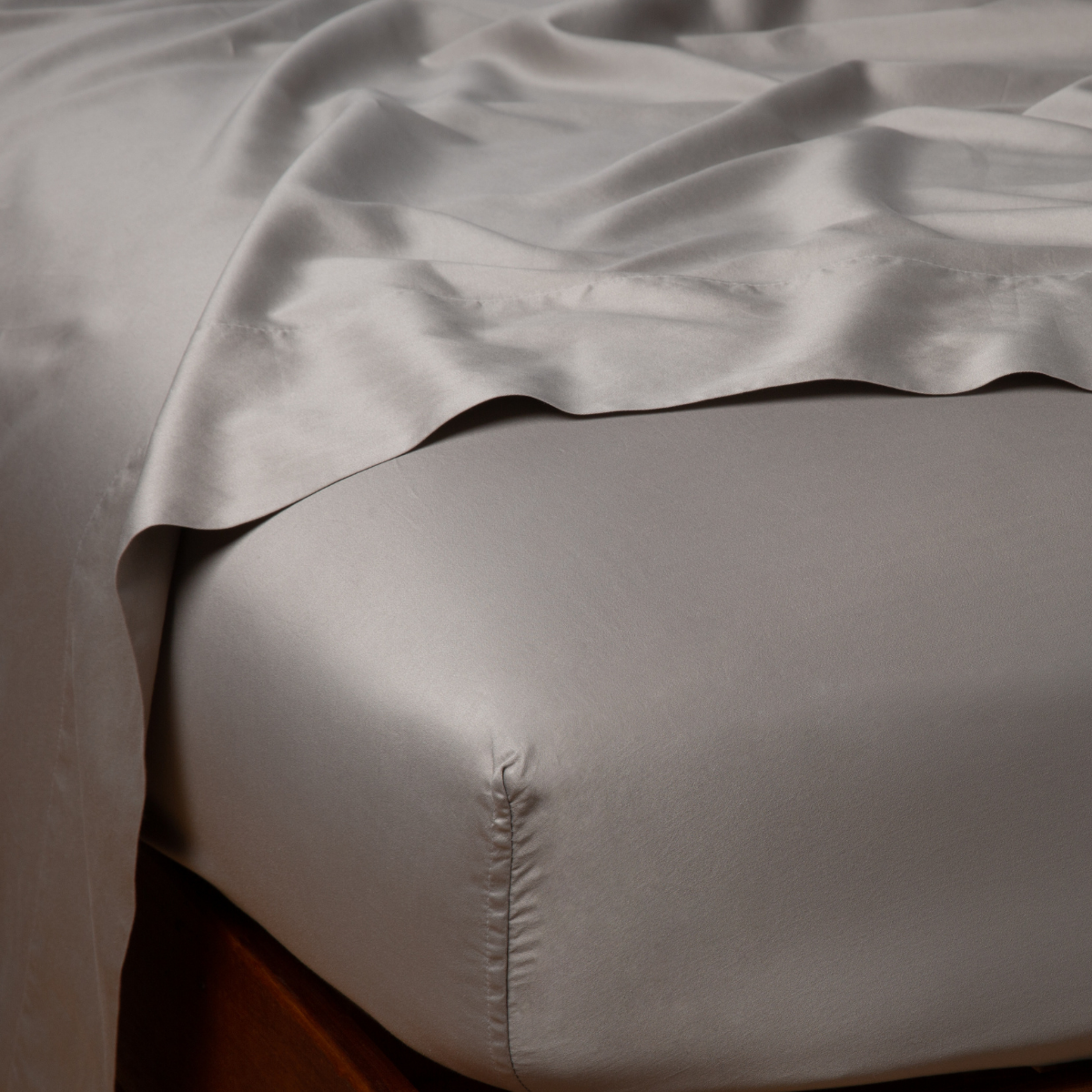 Corner detail of Bella Notte Bria fitted sheet in Fog, showing lustrous satin weave and tailored corner seam.