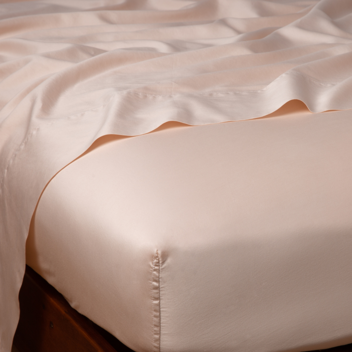 Close-up of Pearl satin fitted sheet corner tucked onto a bed, showing lustrous sheen.