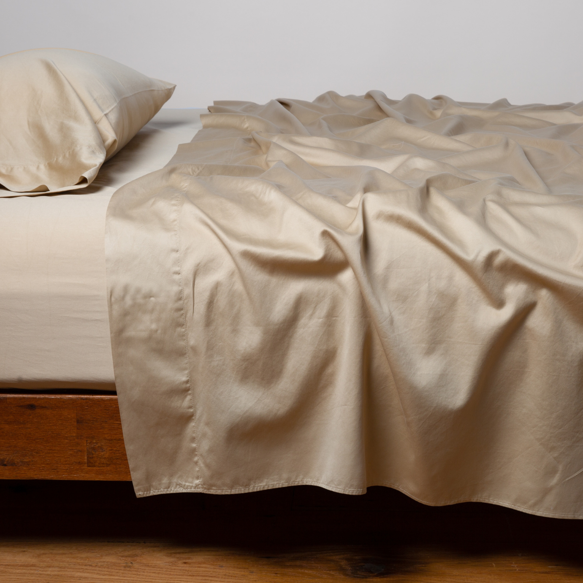 Bella Notte Bria flat sheet in Honeycomb, draped loosely over a low wooden bed.