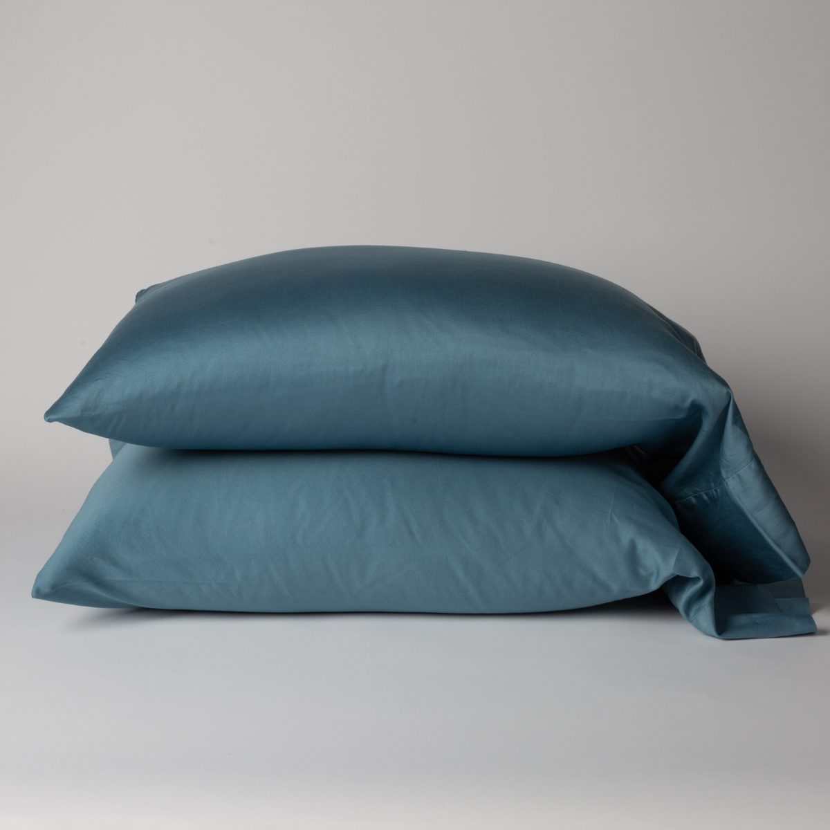 Two Bella Notte Bria pillowcases stacked in Cenote, showing smooth sateen finish and relaxed drape.