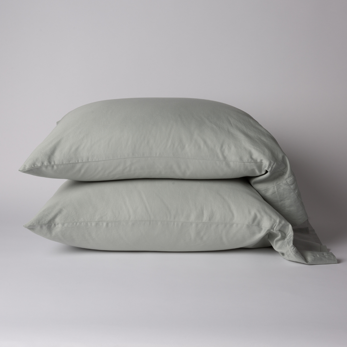 Bria pillowcase pair in Eucalyptus, soft washed linen stacked on a light grey surface.