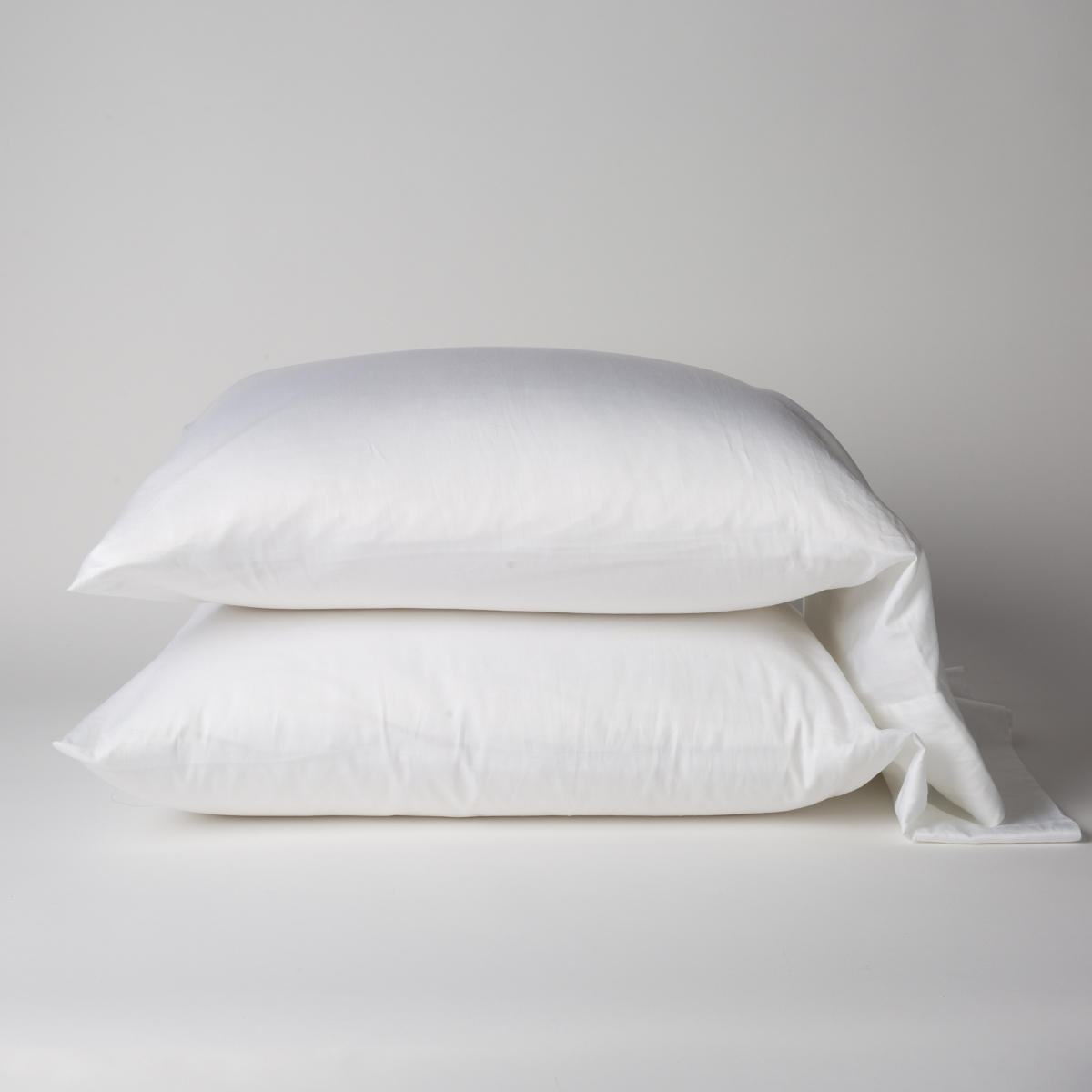 Bella Notte Bria pillowcase in White, two plump cases stacked on grey background.
