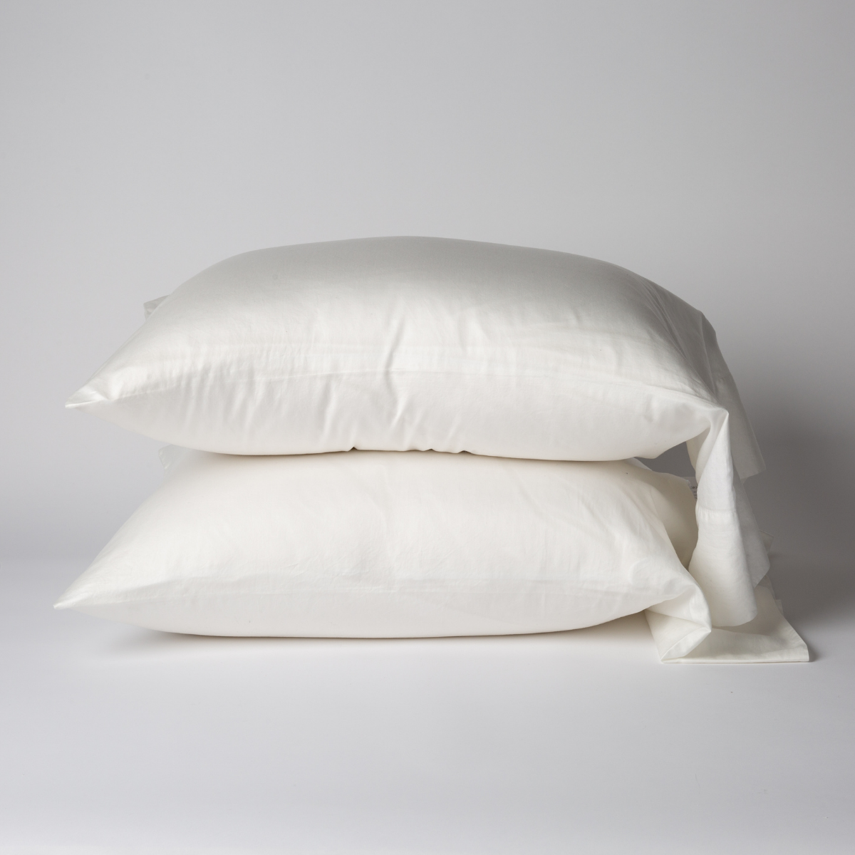 Two Winter White Bella Notte Bria pillowcases stacked, shown against a soft grey background.