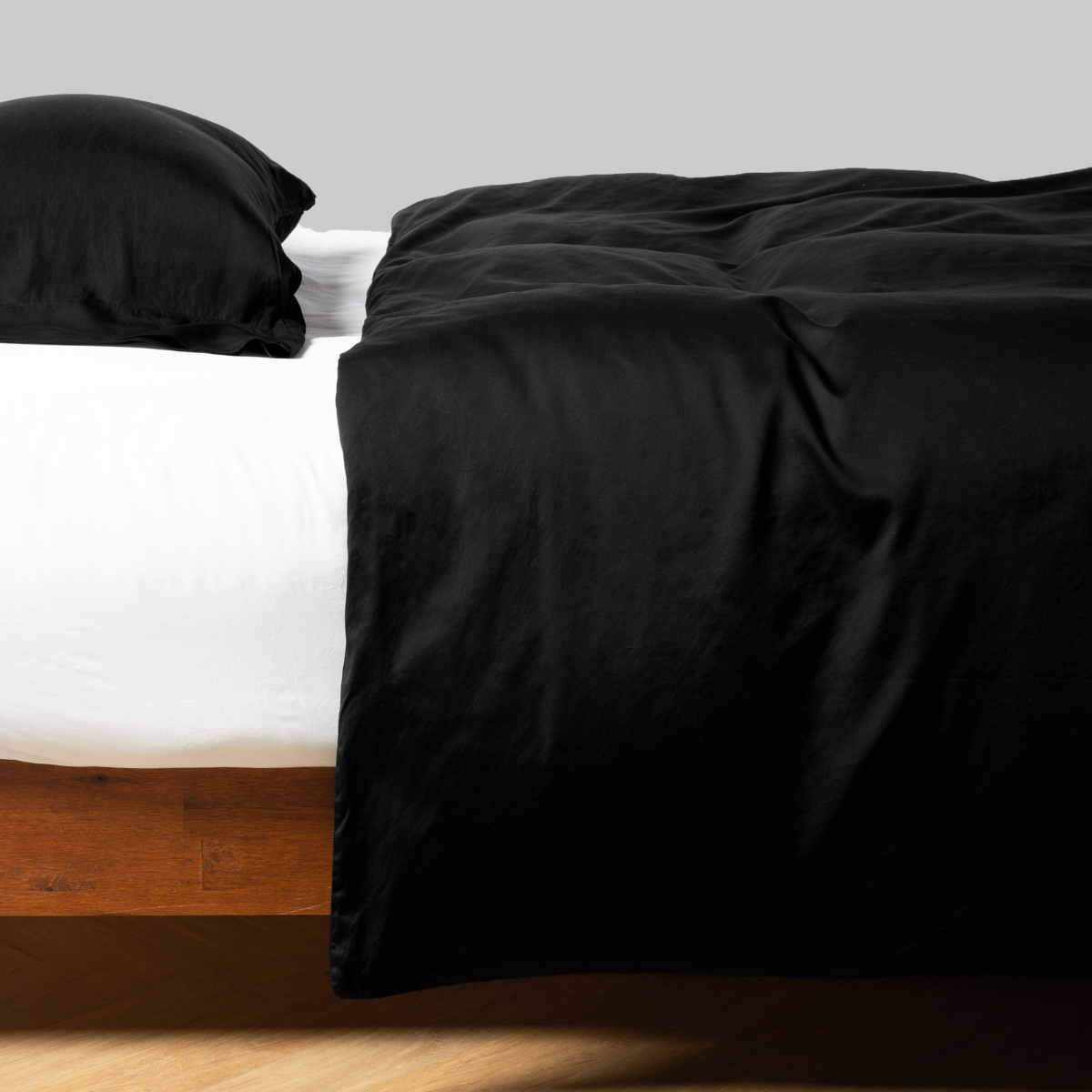 Bria duvet cover in Corvino draped over bed with matching pillowcase, wood frame visible.