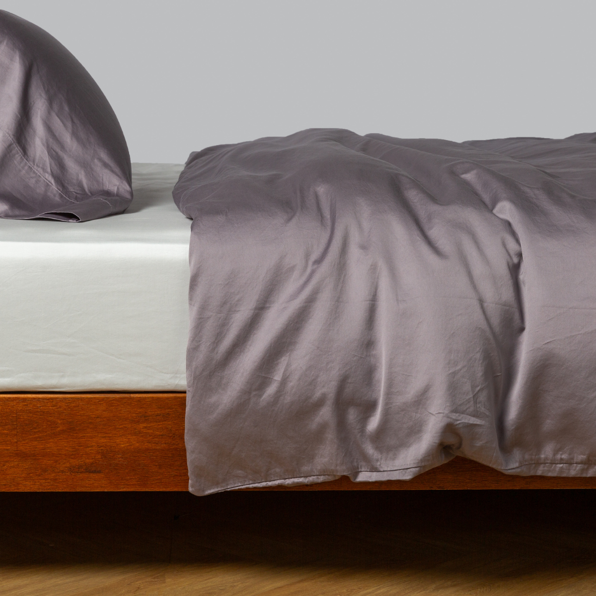 Bella Notte Bria duvet cover in French Lavender, casually draped over a wood-frame bed.