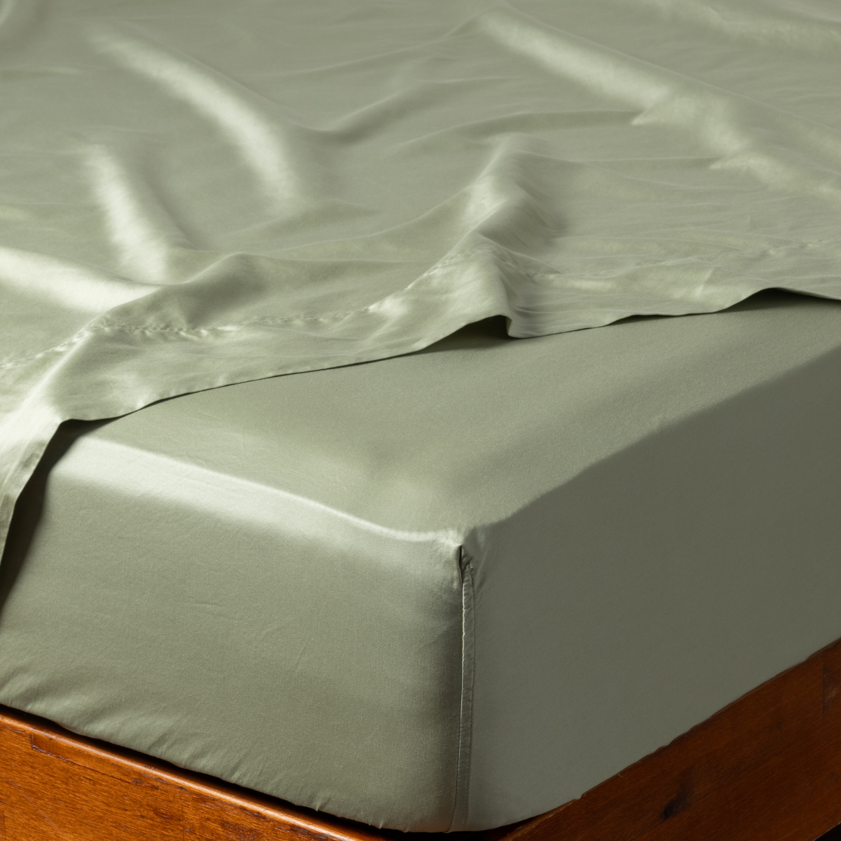 Fitted sheet corner detail showing smooth Desert Sage fabric and deep pocket on wood bed frame.