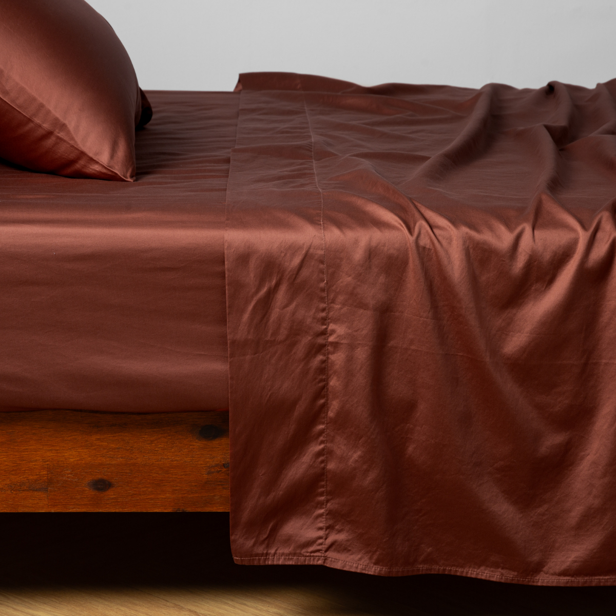 Bella Notte Bria fitted sheet in Autumn draped casually over a wooden bed frame.