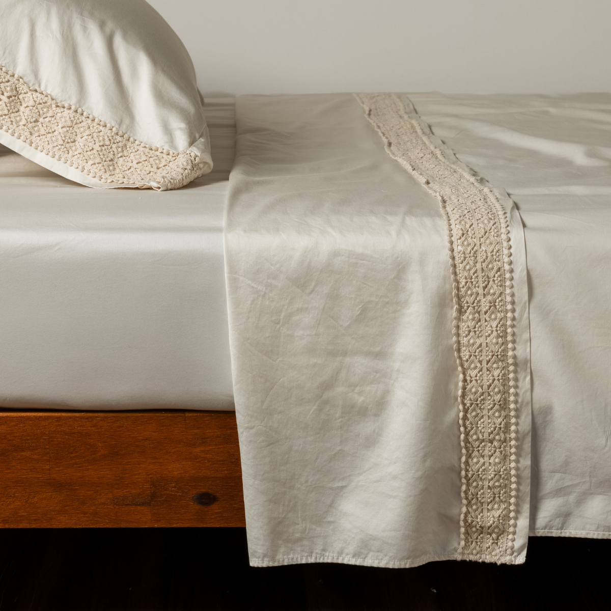 Natural flat sheet draped over bed, showing wide Natural lace trim detail along hem and pillow edge.